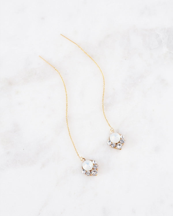 Flatlay of the Celestial Crystal Threader Earrings in gold/white opal.
