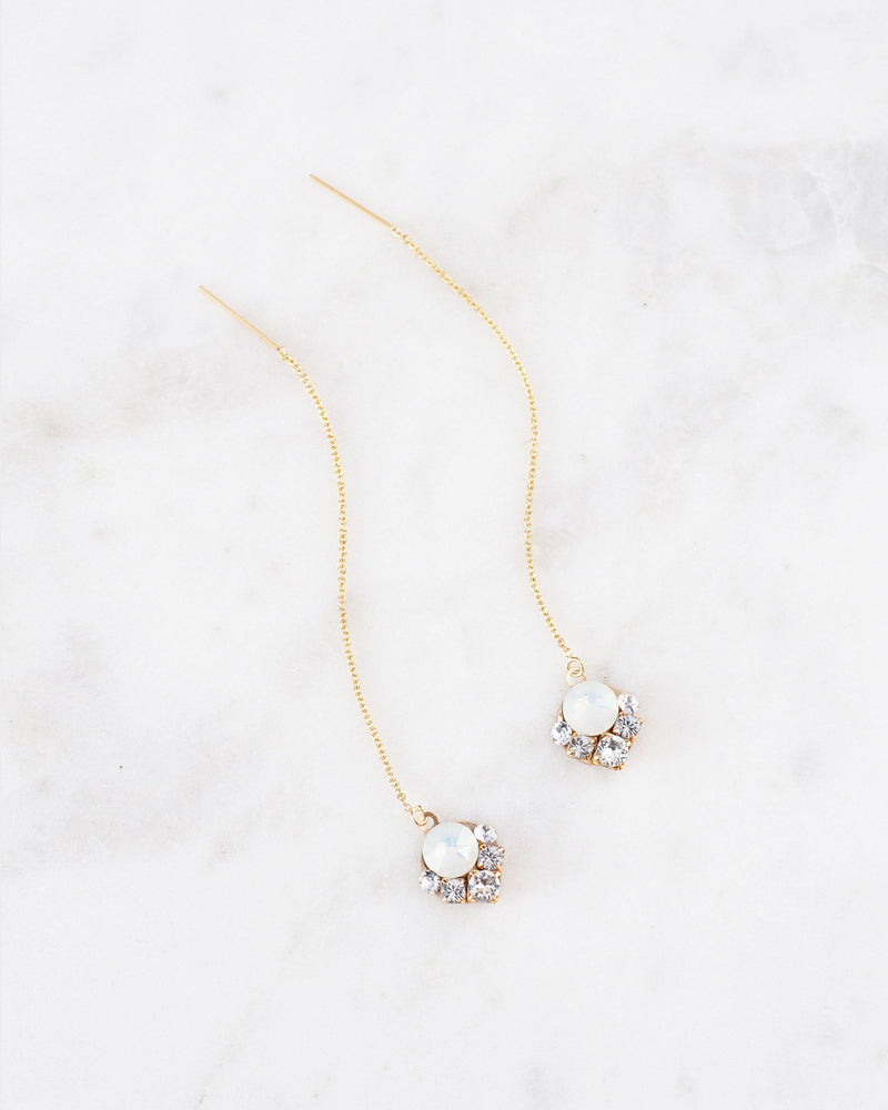 Flatlay of the Celestial Crystal Threader Earrings in gold/white opal.