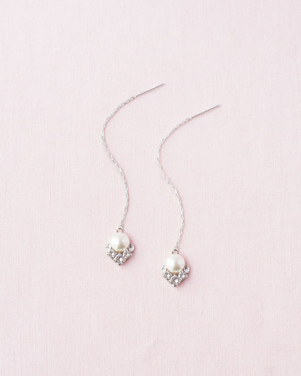 Flatlay of the Celestial Pearl Threader Earrings in silver with cream pearls.
