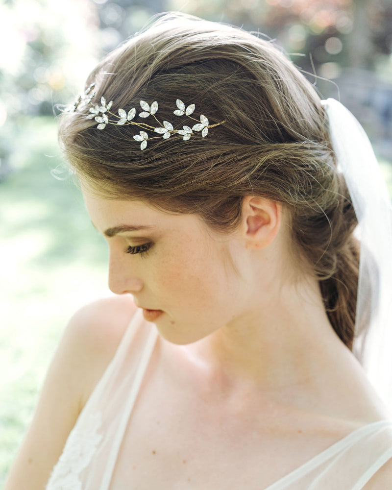 A bride wears a floral crystal hair vine with crystal blossoms and a tulle veil.