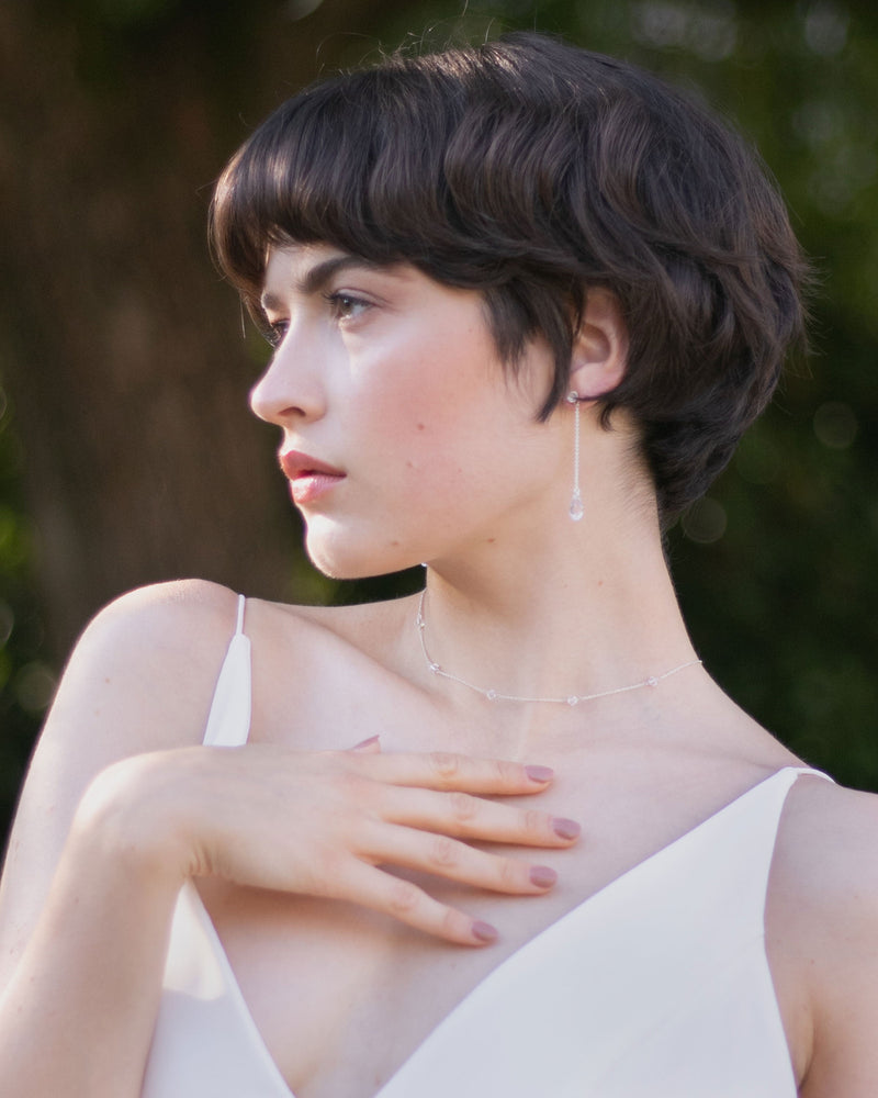 A moderl wears the Dainty Crystal Necklace in silver with the Dewdrop Long Earrings.