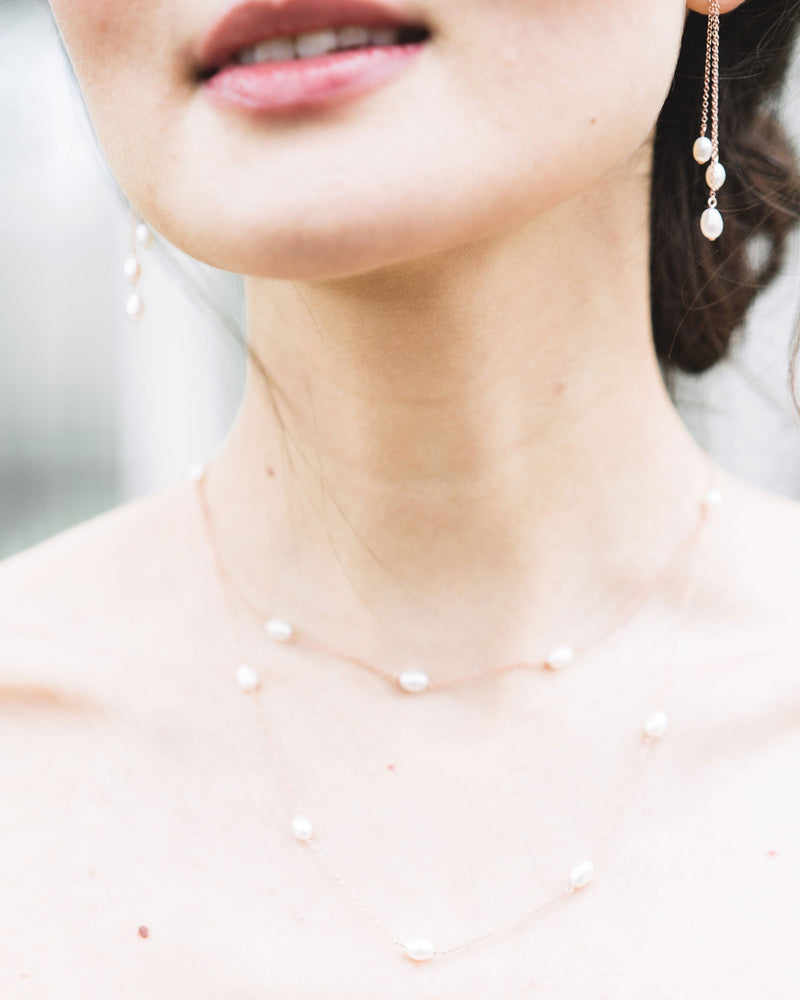 A close-up model view of the dainty layered pearl necklace, paired with the dainty pearl trio earrings.