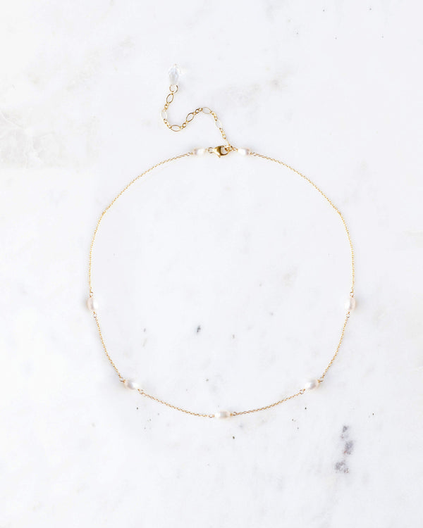 A flatlay of the Dainty Pearl Necklace in gold, with five scattered freshwater pearls on a delicate chain.