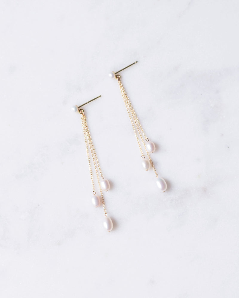 A flatlay of the Dainty Pearl Trio Earrings in gold.