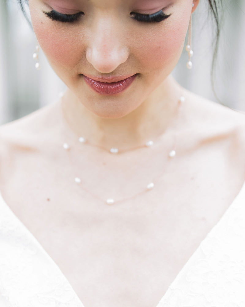 Close up on model of the Dainty Pearl Trio Earrings, paired with the Dainty Pearl Layered Necklace
