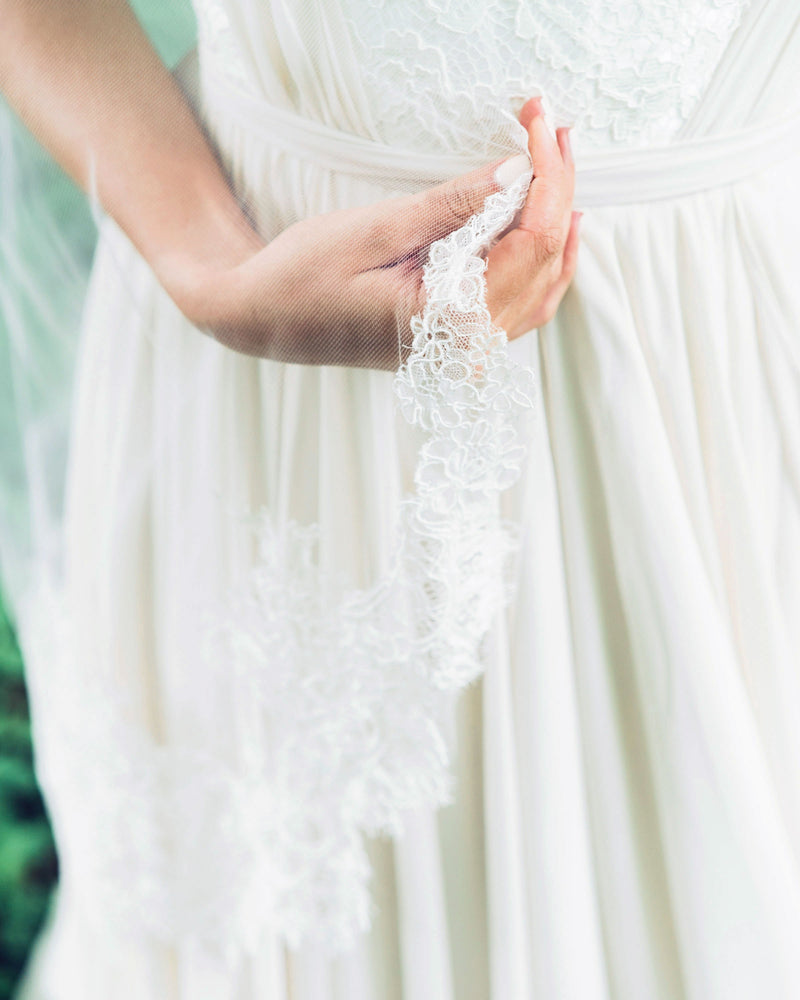 A close model view of the delicate chantilly lace detail on the edge of the Delicate Chantilly Lace Veil.