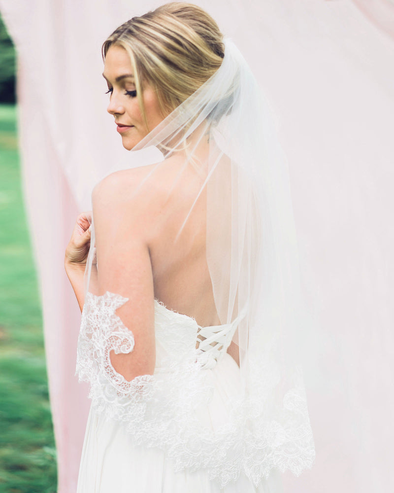 Bride wearing playful waist veil with intricate Chantilly lace.