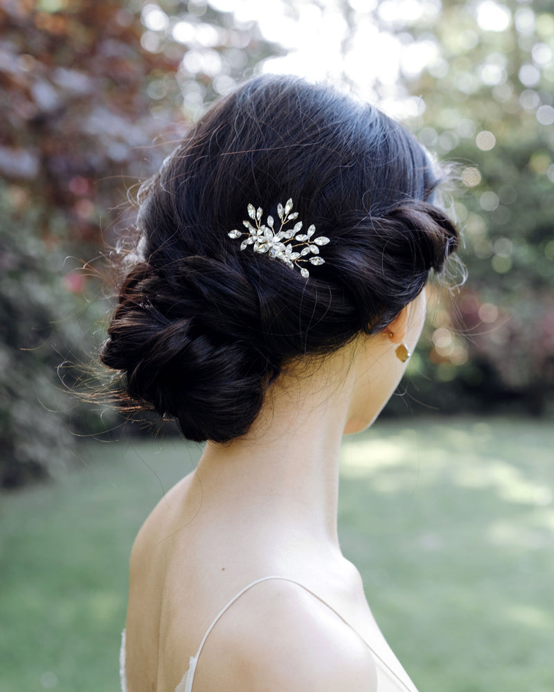 Back view of a dark-haired model wearing an all-crystal version of the Delicate Comb with a low bridal updo.