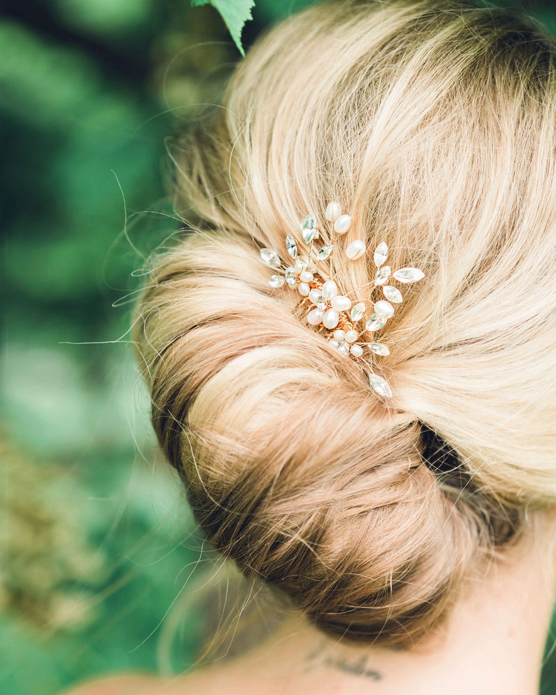 Close model view of the Delicate Comb styled into a modern bridal French twist. The comb is gold with pearls and crystals.