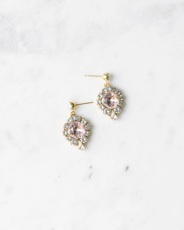 Flatlay of the Enchanted Crystal Drop Earrings in gold with blush crystal centres.