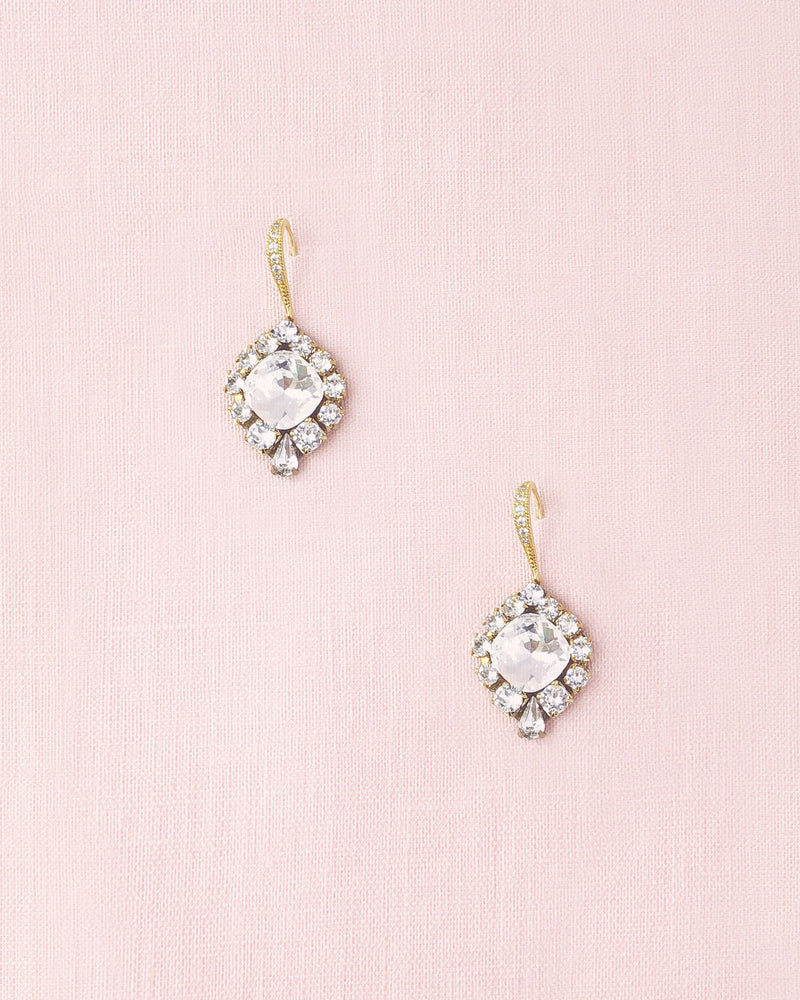 A flatlay of the Enchanted Crystal Drop Earrings in gold with crystal centres. The pave crystal hook option is shown.