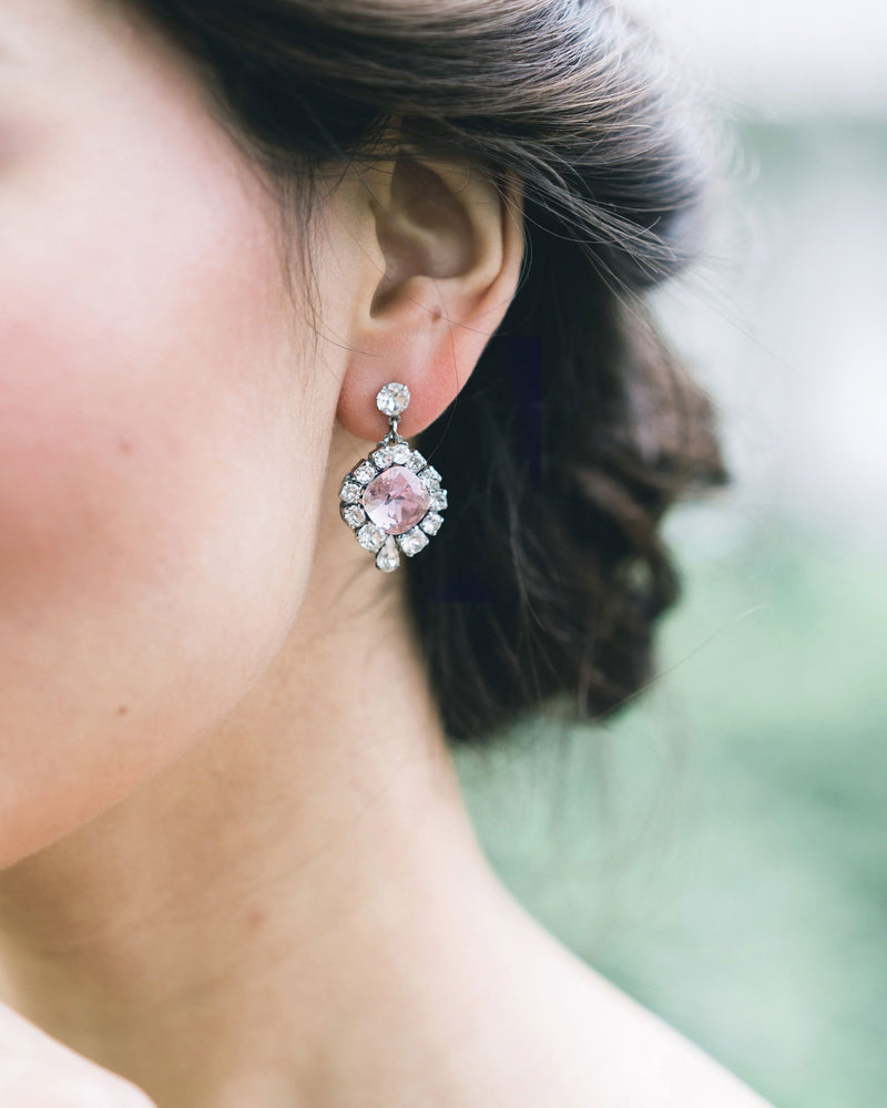 A close model view of a bride wearing the Enchanted Crystal Drop Earrings in gold with blush crystal centres.