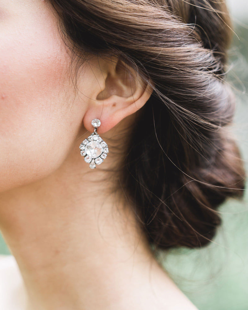 A close model view of a bride wearing the Enchanted Crystal Drop Earrings in silver with crystal centres.