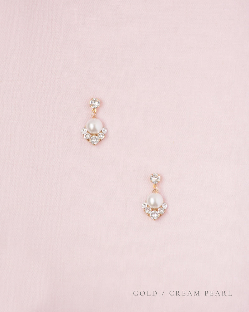 Flatlay of the Celestial Pearl Drop Earrings in gold with cream pearls.
