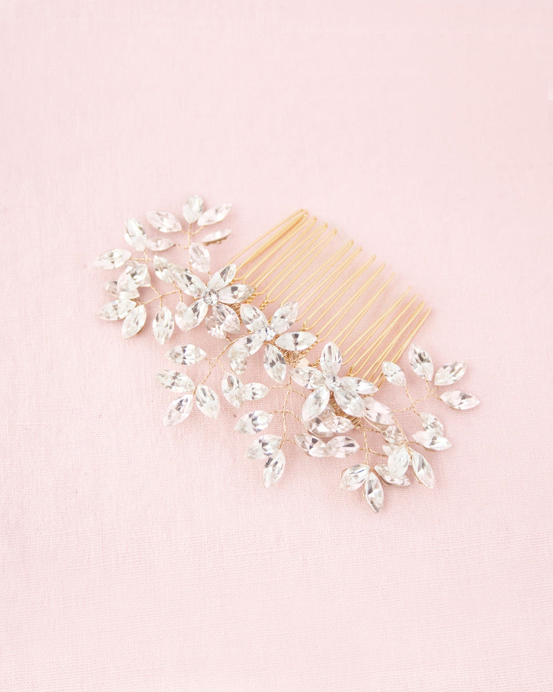 A flatlay on a pink background of the Enchanted Crystal Comb in gold.