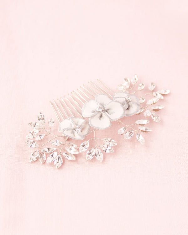 Flatlay on pink background of delicate comb of hand-painted flowers and scattered crystals.