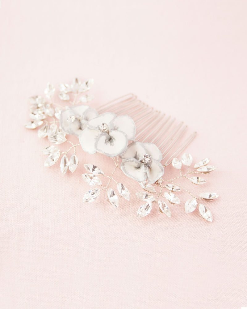 Flatlay on pink background of delicate comb of hand-painted flowers and scattered crystals.