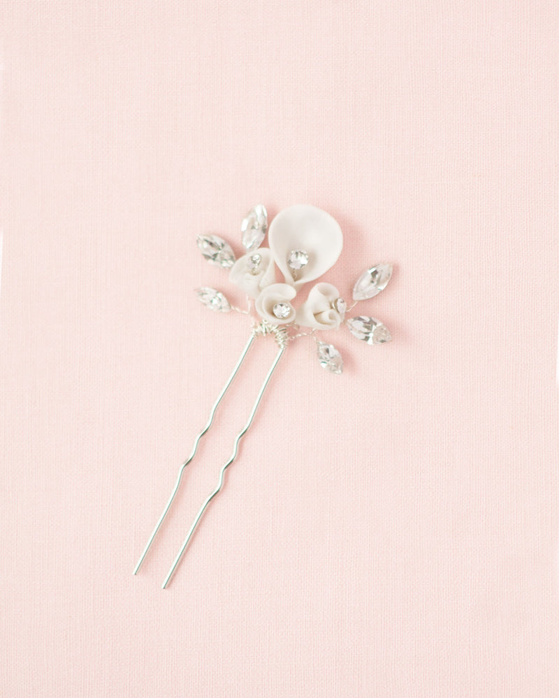 Flatlay on pink background of the Gilded Lily Hair Pin in silver. The white flowers are shown without the hand-painted edge.