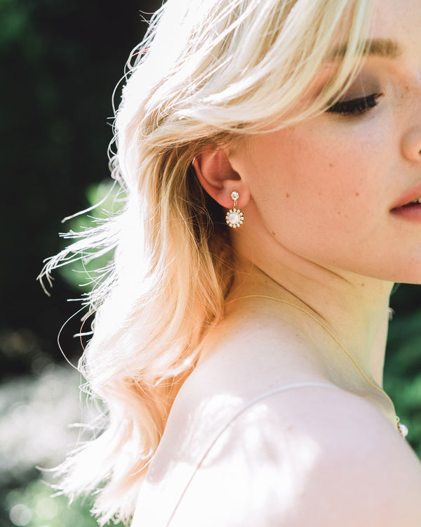 A model with blonde hair wears the Halo Pearl Drop Bridal Earrings in gold with freshwater pearl.
