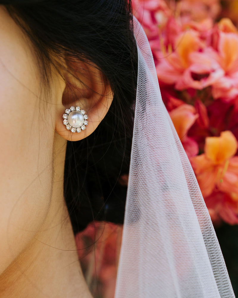 Close on model view of the Halo Pearl Bridal Stud Earrings in silver with white pearls.