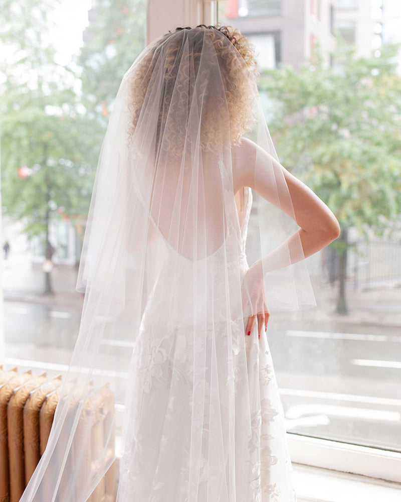 A bride wears the Hibiscus Circular Lace Veil with blusher styled to the back.