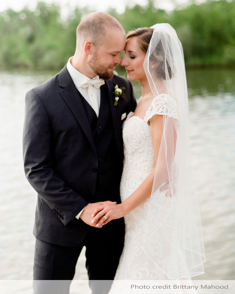 A real bride wears the Leila Veil; a fingertip length veil with delicate ribbon trim.