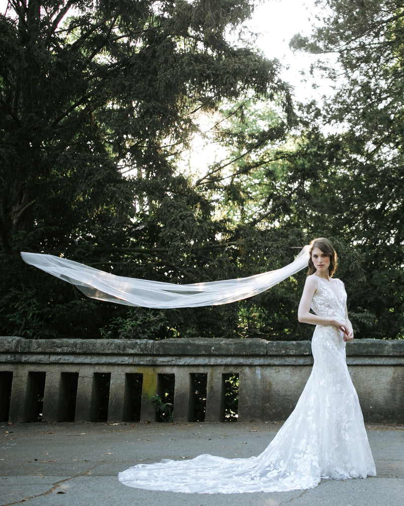 A bride wears a veil that floats in the air behind her. The veil is long, with no trim.