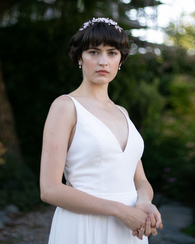 A bride with a pixie hairstyle wears the Lily Floral Crown in silver with the petite pearl drop earrings.