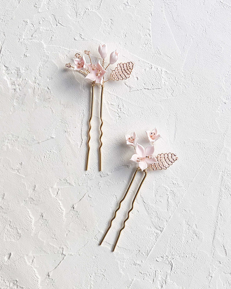 Flatlay view of the set of two Lily Floral Hair Pins in gold with blush flowers and blush seed beads.