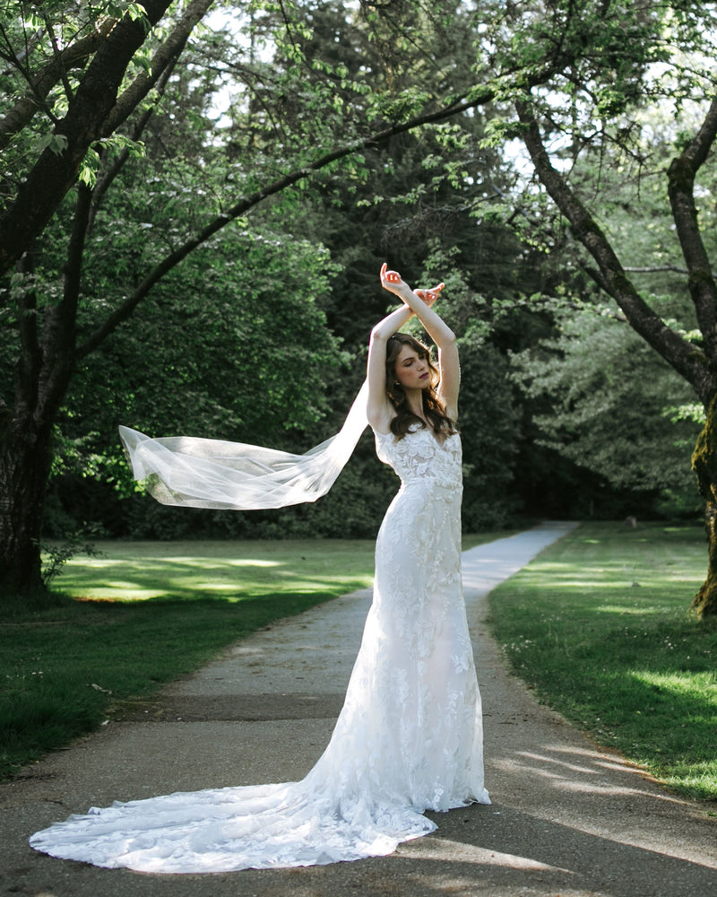 A bride wears a veil that floats in the air behind her. The veil is waltz length, with no trim.