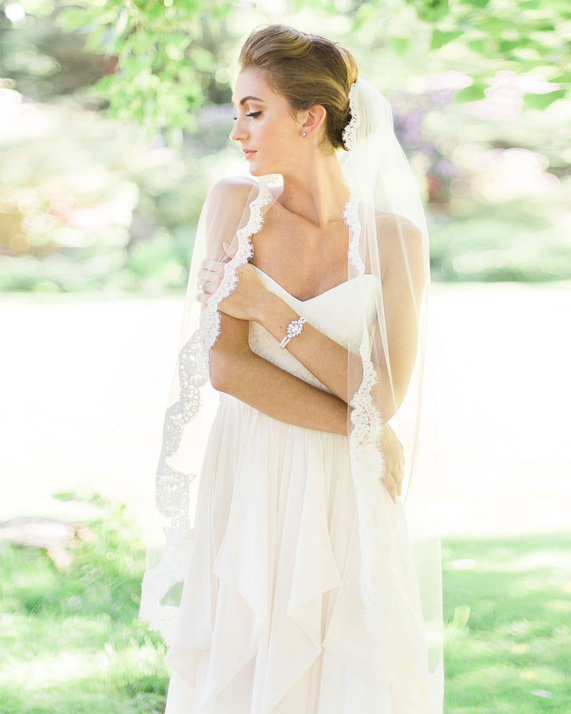 A bride wears the Magnolia Lace Veil in fingertip length.