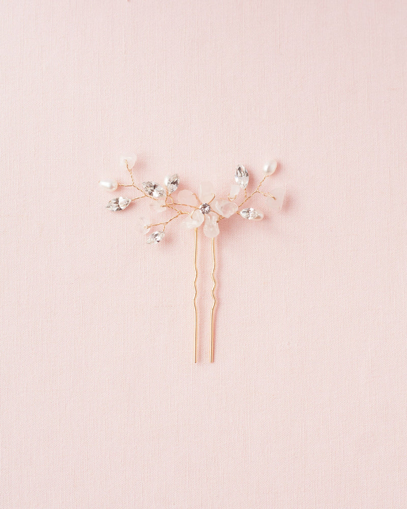 Flatlay on pink background of the Moonflower Bridal Comb in gold, with rose quartz gemstones, pearls, and crystals.