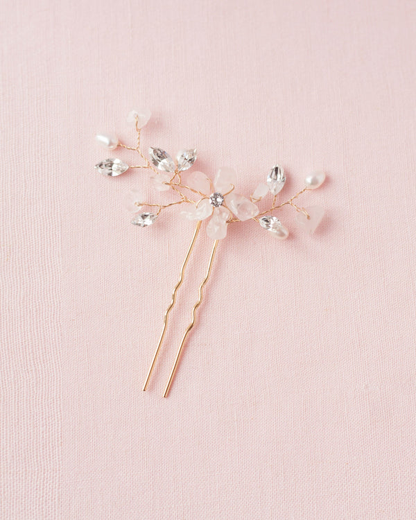 Flatlay on pink background of the Moonflower Bridal Comb in gold, with rose quartz gemstones, pearls, and crystals.