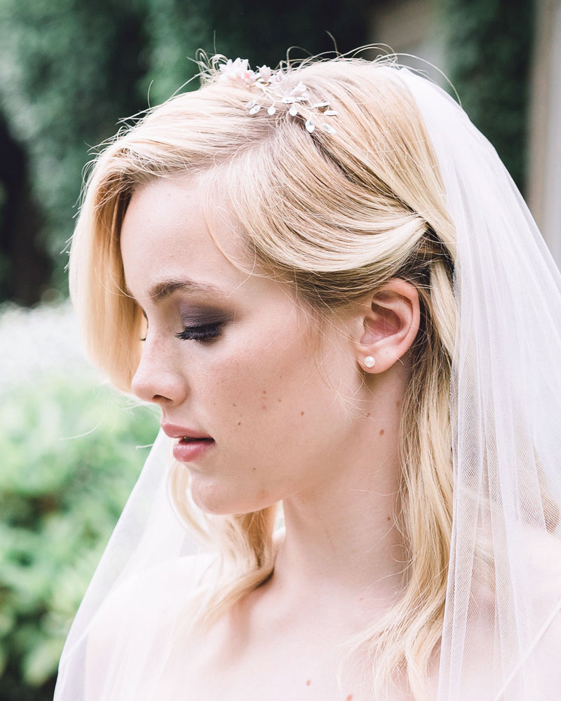 A bride wears the Petite Pearl Stud Earrings, paired with a hair vine and veil.