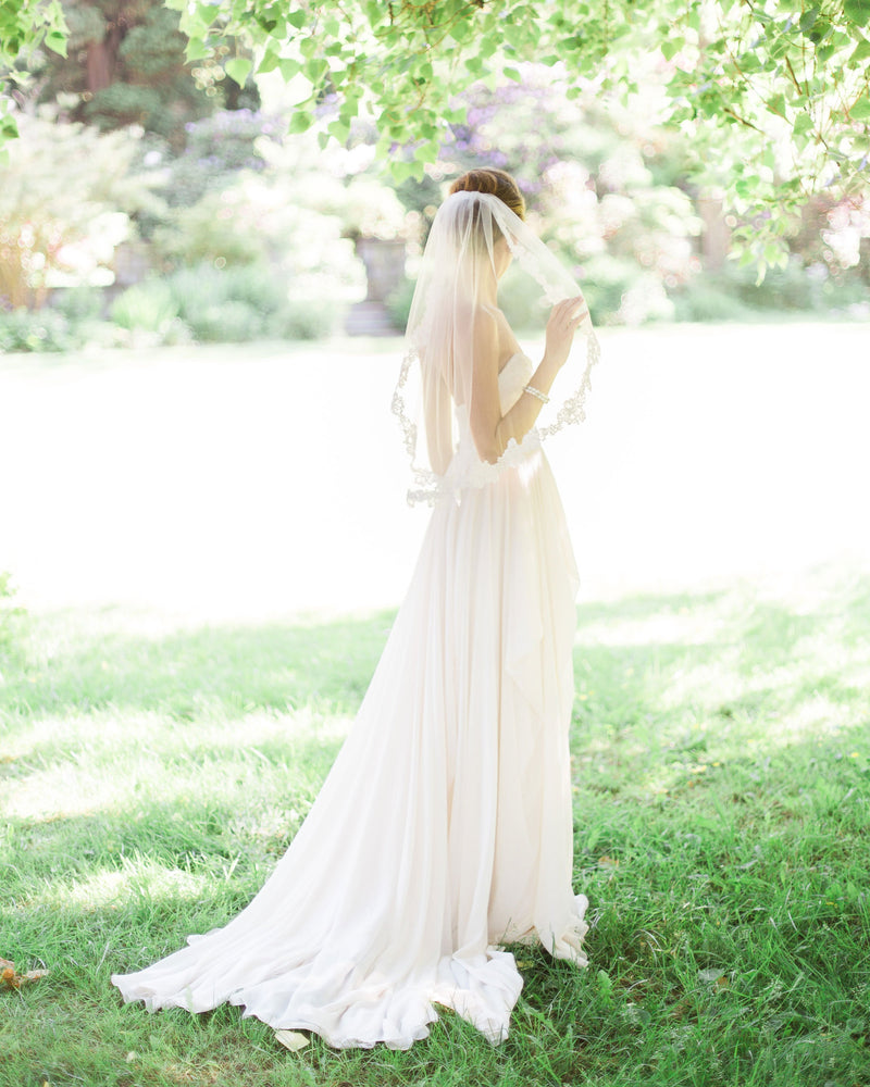 A faraway view of a bride wearing the Peony Short Lace Veil.
