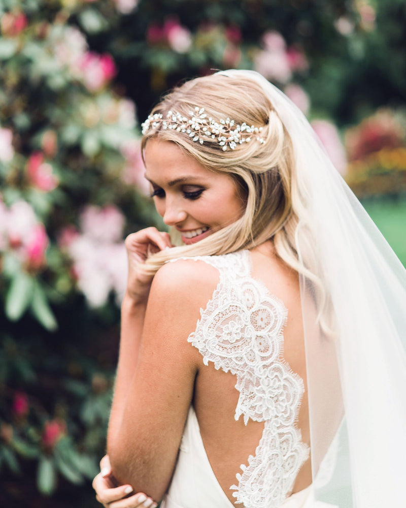 A model wears a dramatic hair vine for brides with pearls and scattered crystals in rose gold.