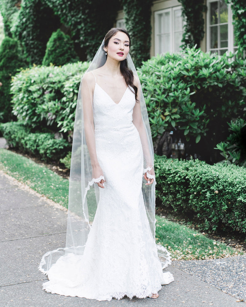 A bride wears the Senna Lace Chapel Veil with a lace scallop edge and no gathers.