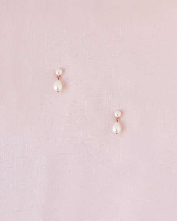 Flatlay of the Teardrop Pearl Petite Drop Earrings in rose gold.