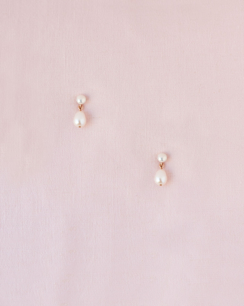Flatlay of the Teardrop Pearl Petite Drop Earrings in rose gold.