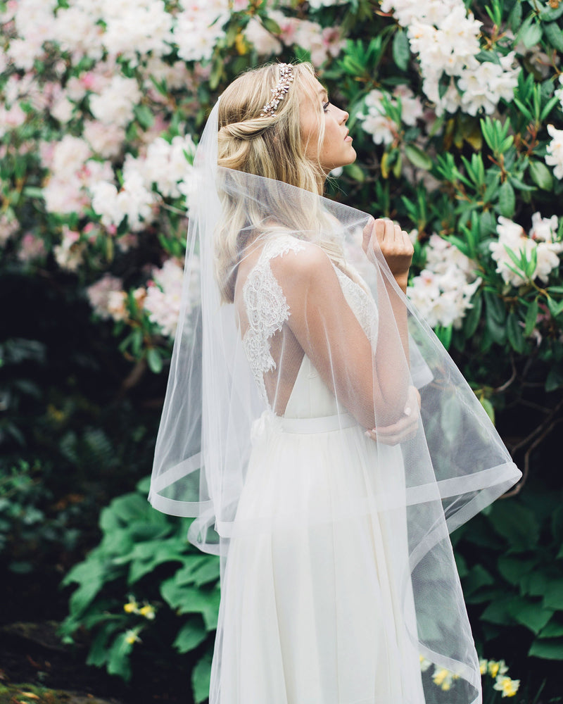 A bride wears the Zahra Horsehair Trim Veil in fingertip length, with the blusher worn to the back.