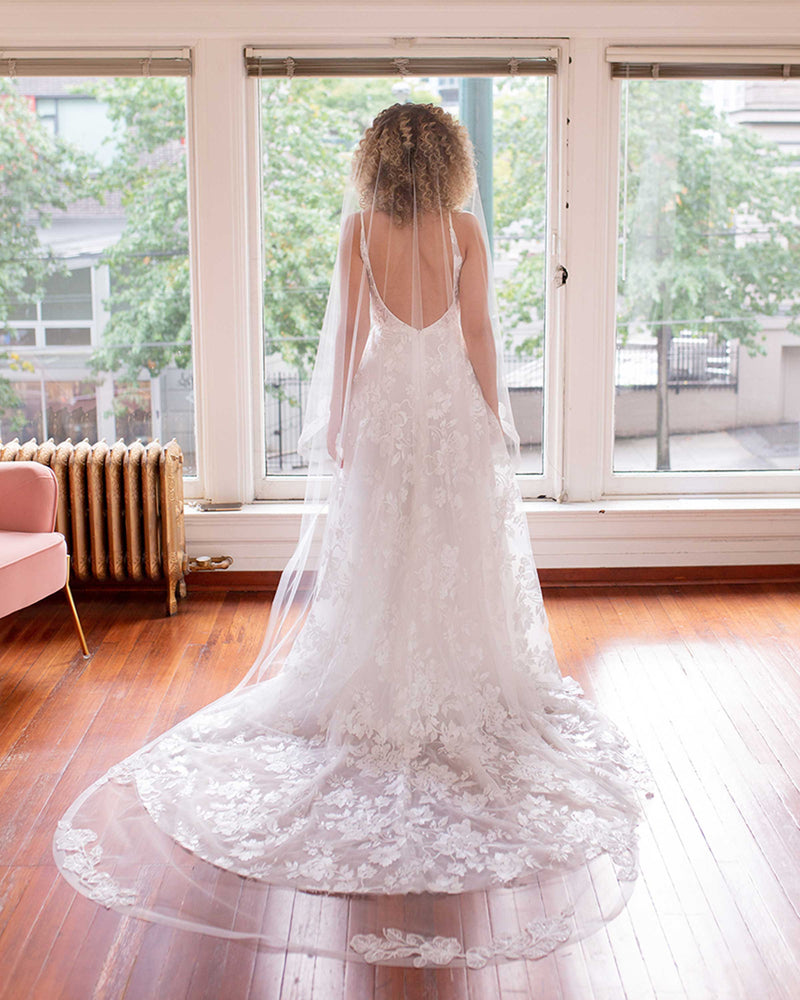 Back view of a bride wearing the Zinnia Veil with beaded lace and horsehair accents in extended chapel length.